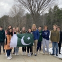 YES student Aleeza standing outside with a group of peers, holding the Pakistani flag.