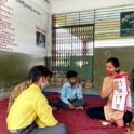 An Instructor Is Teaching Three Children All Sitting On The Floor