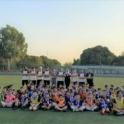 A wide photo of the large group of participants and coaches posing on the soccer field
