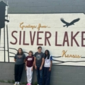 Abbiramyy with her host siblings in front of a sign saying Greetings from Silver Lake, Kansas