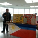 Matias standing in front of a table with Filipino flag and cultural materials