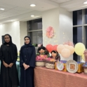 Three alumni standing next to a table with balloons and toys
