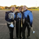  Three teens in blue and black band uniforms pose in a parking lot with their instruments