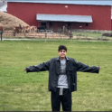 Youssef smiling on a farm with his arms spread while snow falls